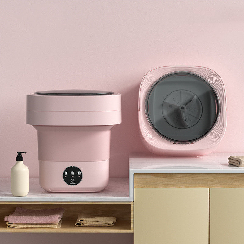 Pink mini foldable washing machine open on a counter beside a view of its grey spin drum
