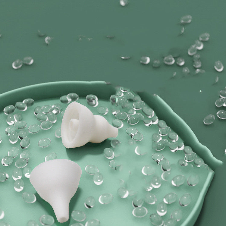 Two detachable white silicone nozzle tips on a green dish surrounded by water droplets