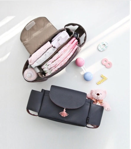 Stroller bag's top compartment open showing diapers and wipes stored inside, with a matching black bag below