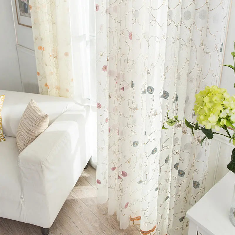 Garden embroidered sheer curtain panel hanging in a bright living room window