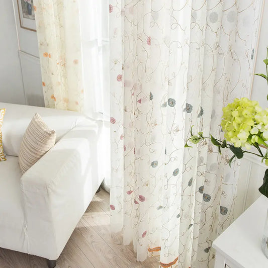 Garden embroidered sheer curtain panel hanging in a bright living room window