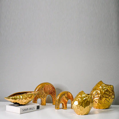 Full set of four gold-plated geometric ceramic vase shapes styled together with a book
