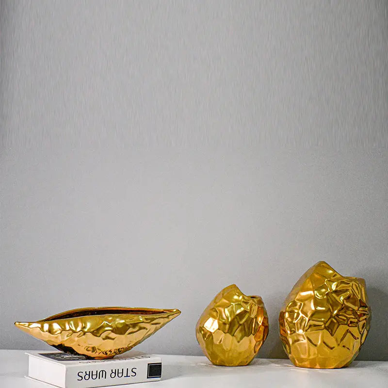Gold-plated geometric ceramic vases styled in a pair with a book on a gray background