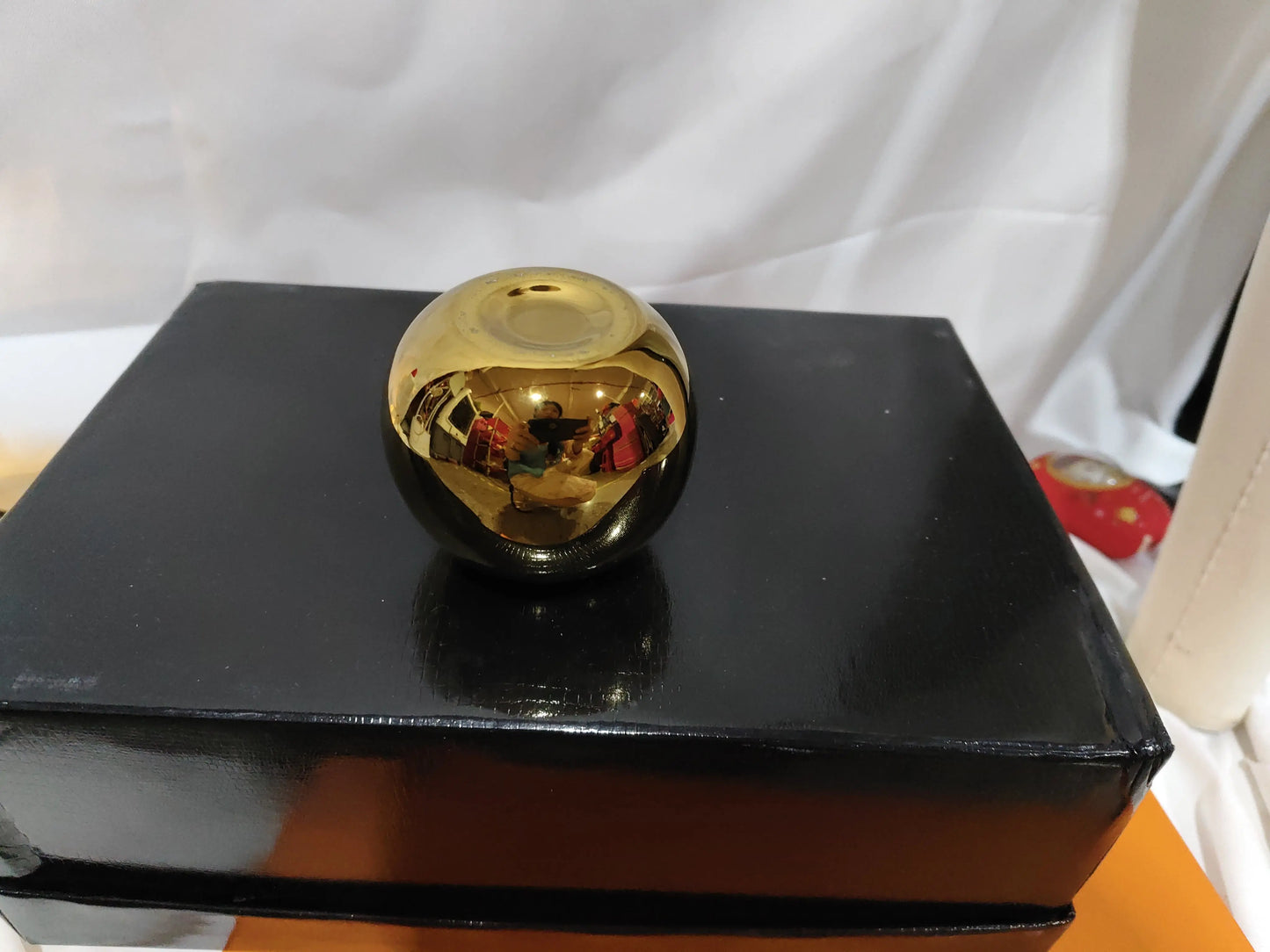 Gold electroplated ceramic vase displayed on a black stand with books
