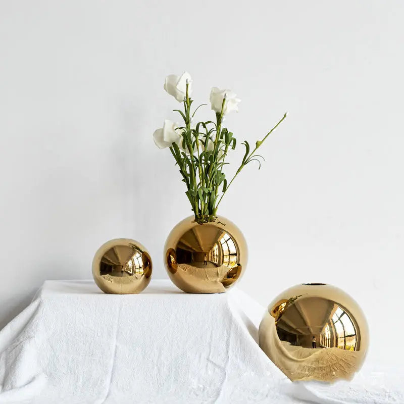 Gold electroplated ceramic vase with white flowers on a styled tabletop