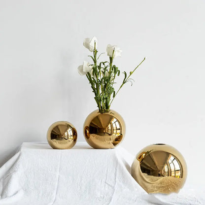 Gold electroplated ceramic vase with white flowers on a styled tabletop
