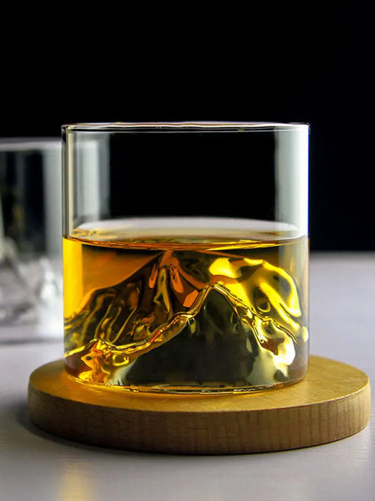 Japanese-style whiskey glass with amber whiskey and a mountain-shaped ice cube on a wood coaster