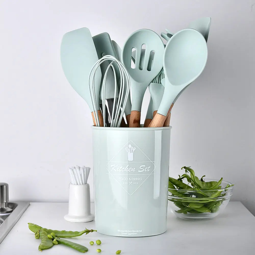 Silicone and wood handle kitchen utensil set laid out on a white background