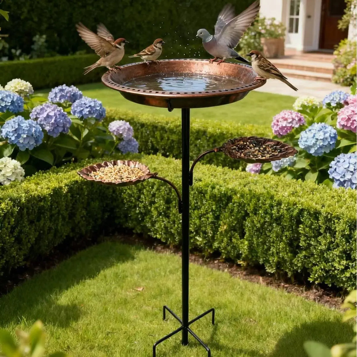 Metal geometric ground insert bird feeder in a lush garden with birds feeding