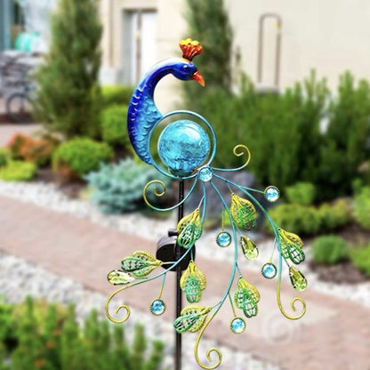 Solar metal peacock garden lamp styled against a house with greenery