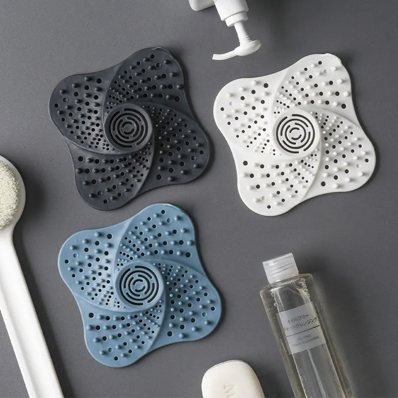 Silicone drain hair catchers in three colors styled with shower props in a flatlay