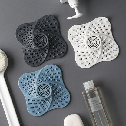 Silicone drain hair catchers in three colors styled with shower props in a flatlay